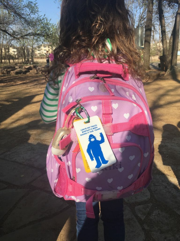 young girl walking with a backpack on, with leave no trace hangtags dangling from her pacl