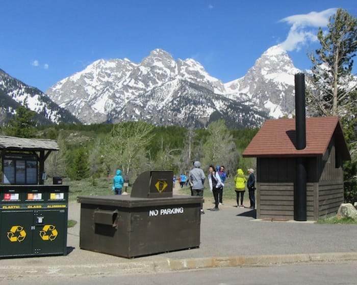 Trash cans at a trailhead with the backdrop of snow-capped mountains