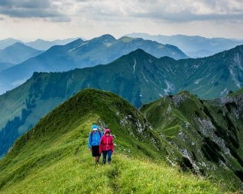Two people hiking along a ridge line in the mountains.