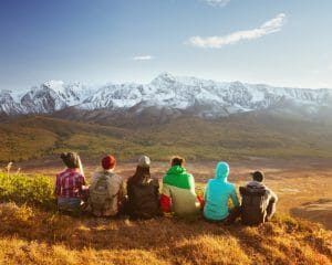 Groupe de jeunes adultes assis en rang et regardant les montagnes enneigées au loin.
