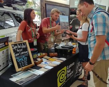 Two Leave No Trace traveling team members providing information to two inquiring visitors during a booth event.