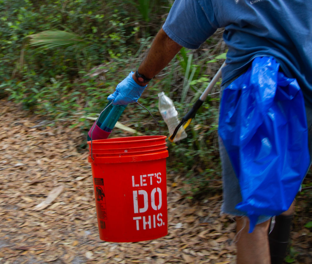 A volunteer puts litter in a bucket.