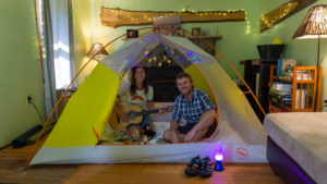 Two leave no trace traveling trainers posing in their tent in their living room.