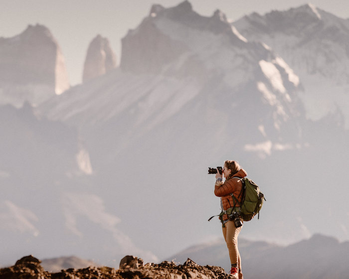 Photographer looking through lens of camera in mountainous backcountry area