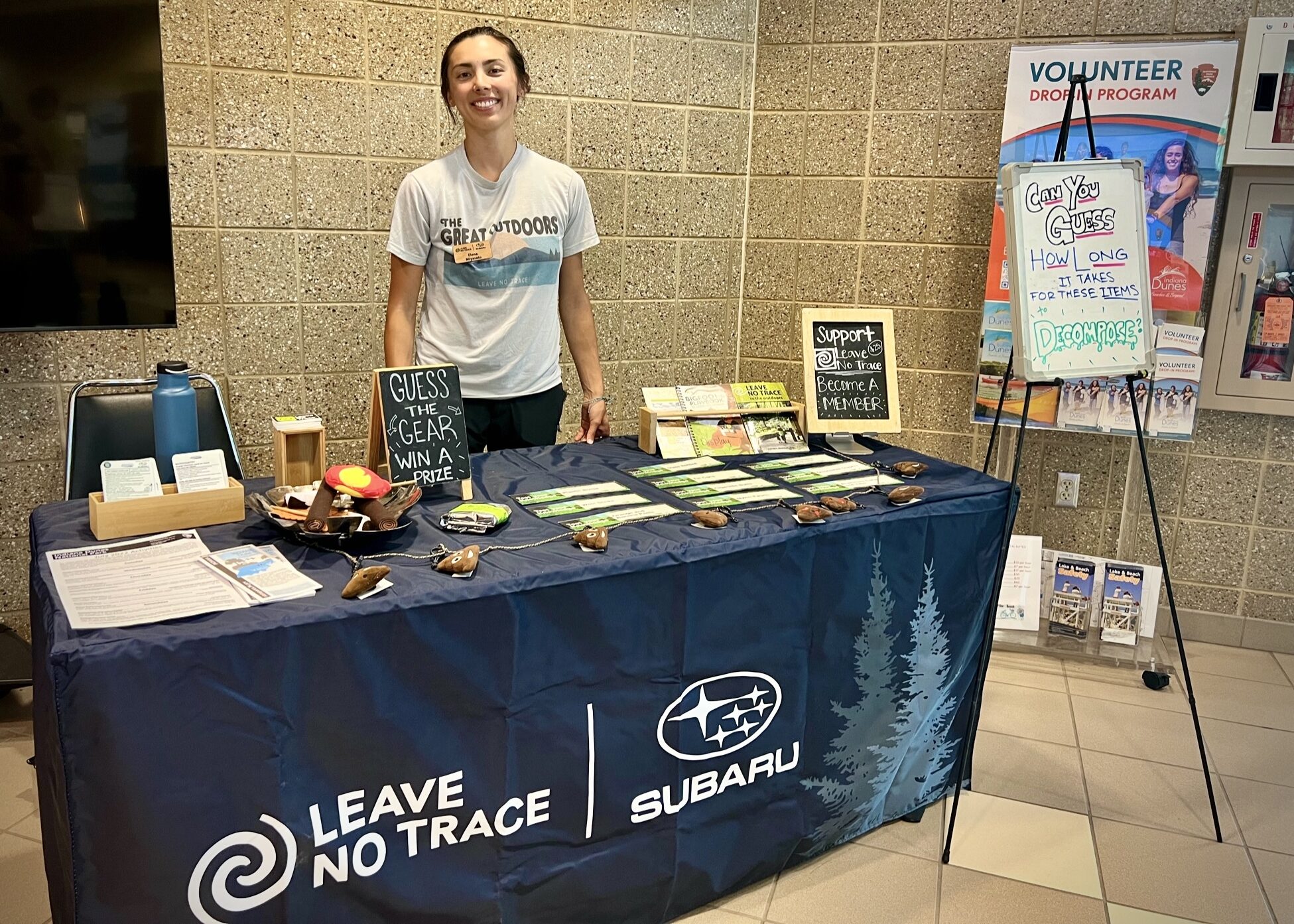 Leave No Trace educator standing behind an outreach table with games and resources set out on the table.