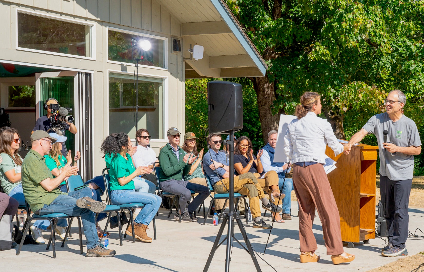 Dana Watts, the executive director of Leave No Trace, accepts funding from Airbnb representatives at an outdoor podium ceremony.